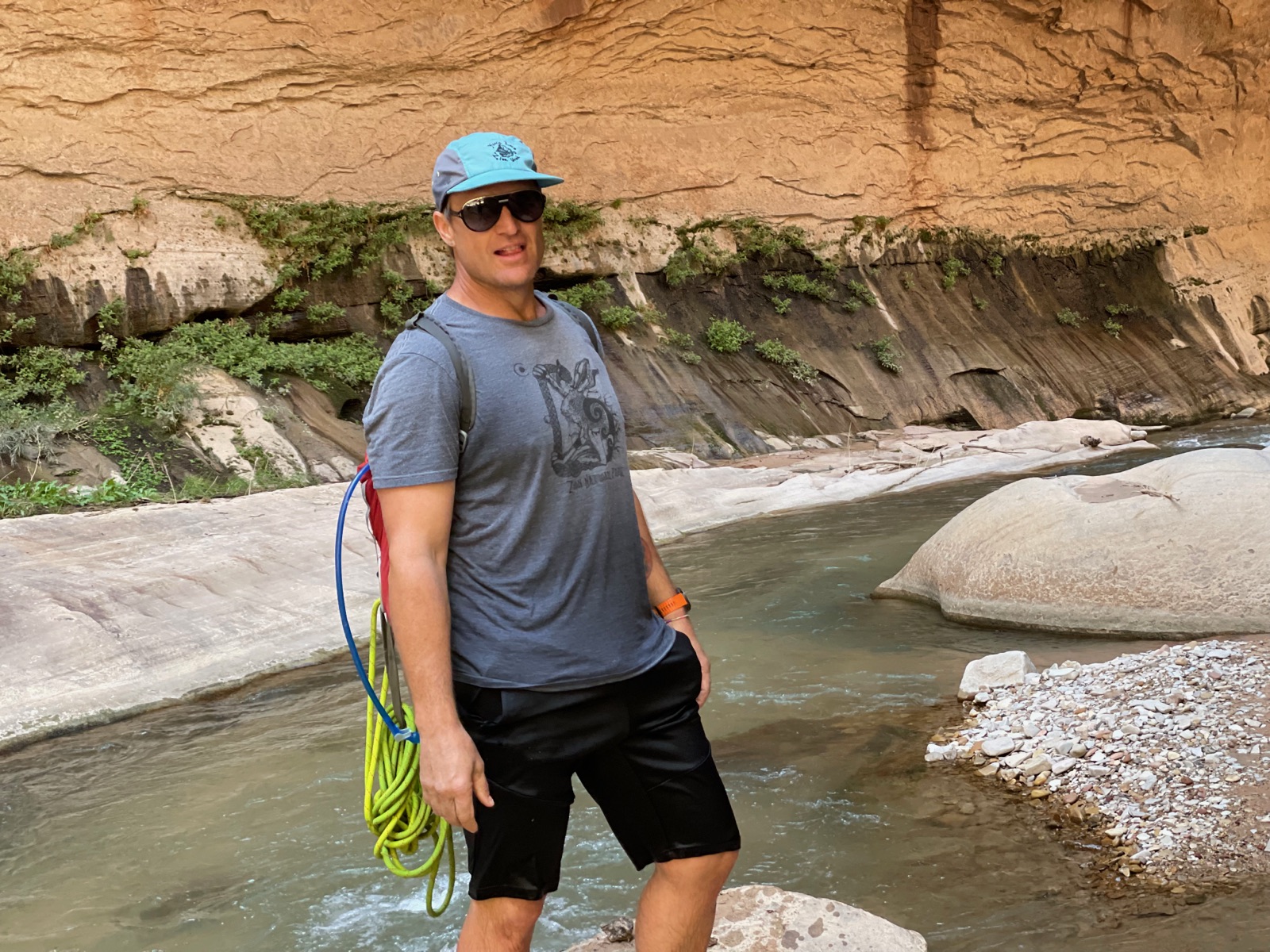 Cody with a rope over his shoulder in a river canyon